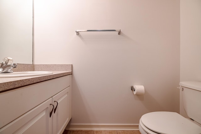 bathroom featuring toilet, baseboards, and vanity