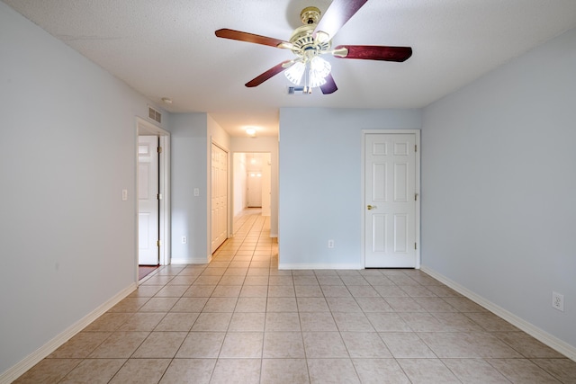 spare room with light tile patterned floors, visible vents, baseboards, and ceiling fan
