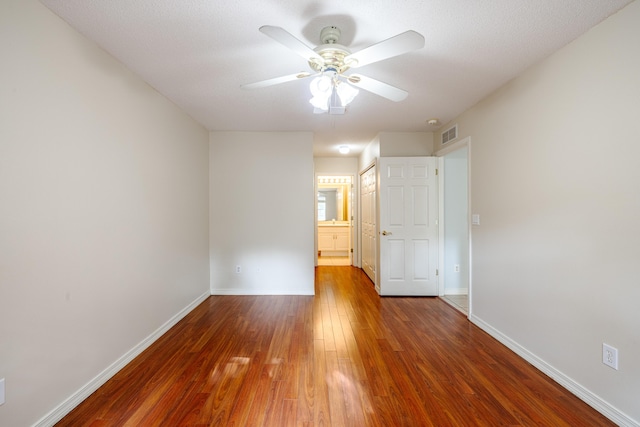 empty room featuring baseboards, visible vents, a ceiling fan, and wood finished floors