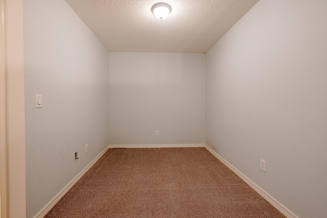 spare room featuring a textured ceiling, carpet floors, and baseboards