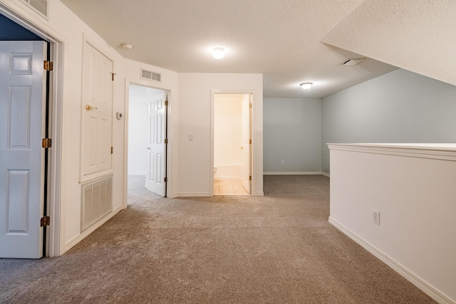 carpeted spare room with baseboards, visible vents, and a textured ceiling