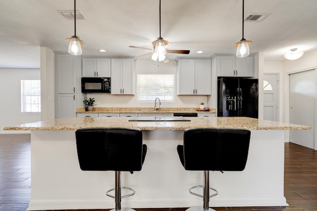 kitchen with a breakfast bar, dark wood finished floors, visible vents, a kitchen island, and black appliances