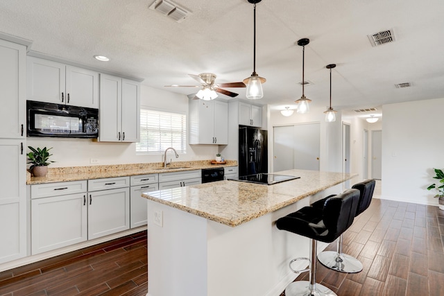 kitchen with dark wood-style flooring, black appliances, visible vents, and a sink