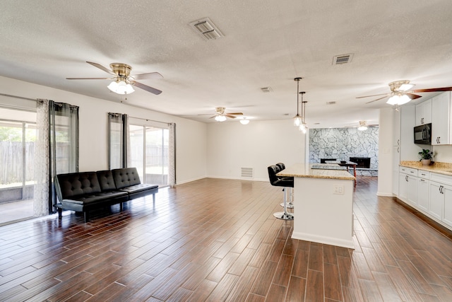 kitchen with a ceiling fan, black microwave, open floor plan, and visible vents