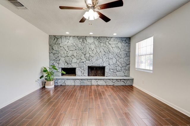 unfurnished living room featuring wood finished floors, a ceiling fan, a fireplace, visible vents, and baseboards