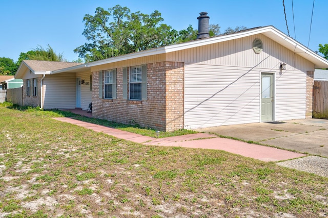 view of property exterior with brick siding and fence