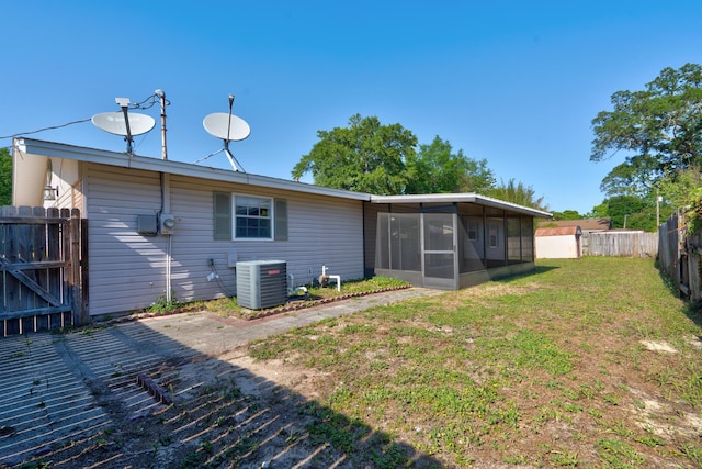back of property with cooling unit, a sunroom, a fenced backyard, and a yard