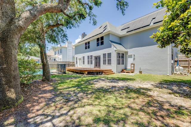 2812 Arnold Palmer Ct, Shalimar, FL 32579 - back of house with stucco siding, a deck, roof mounted solar panels, a chimney, and a swimming pool