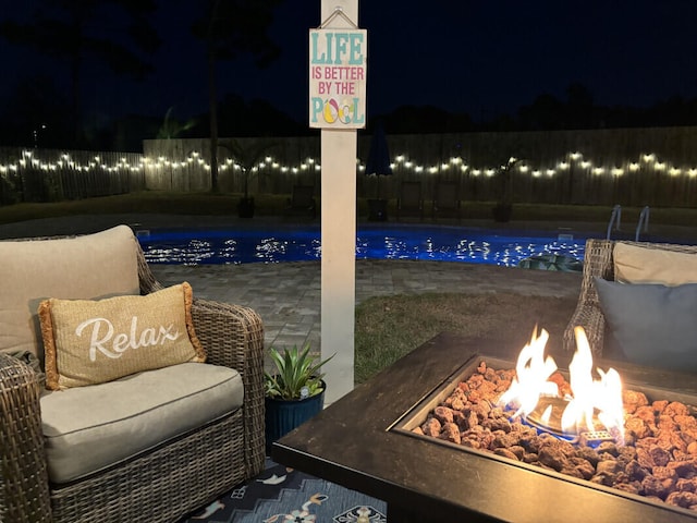 patio at night featuring a fenced backyard, an outdoor fire pit, and a fenced in pool
