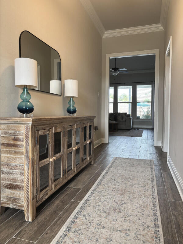 foyer entrance featuring crown molding, wood tiled floor, baseboards, and a ceiling fan