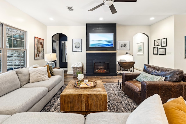 209 Forest Park Dr, Santa Rosa Beach, FL 32459 - living area with arched walkways, a ceiling fan, wood finished floors, a large fireplace, and baseboards