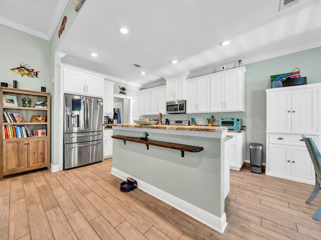 1516 Cadence Lp, Cantonment, FL 32533 - kitchen with white cabinetry, ornamental molding, stainless steel appliances, and light wood-style floors