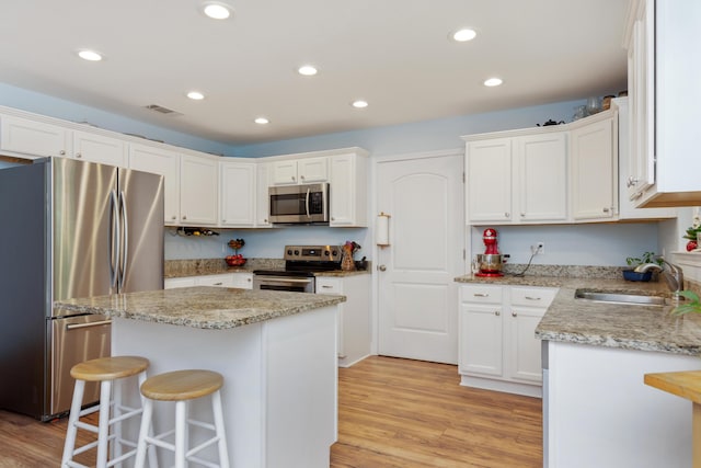 511 Oak Ave, Niceville, FL 32578 - kitchen with appliances with stainless steel finishes, a sink, a kitchen island, a breakfast bar, and white cabinets