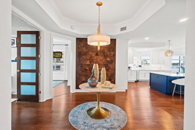 interior space with crown molding, a raised ceiling, visible vents, and dark wood finished floors