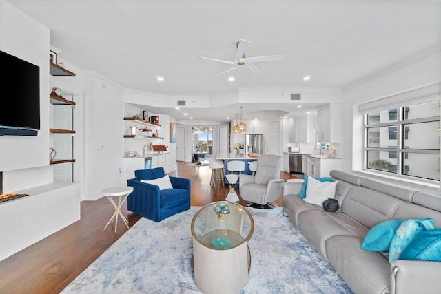 living room with wood finished floors, a ceiling fan, visible vents, ornamental molding, and recessed lighting