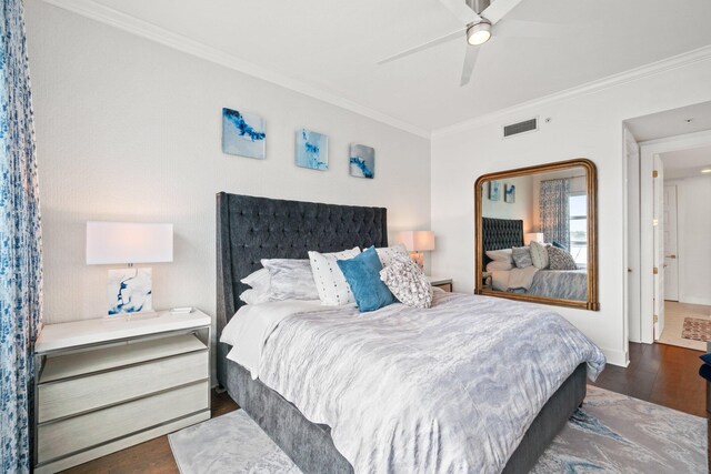 bedroom with a ceiling fan, ornamental molding, visible vents, and wood finished floors