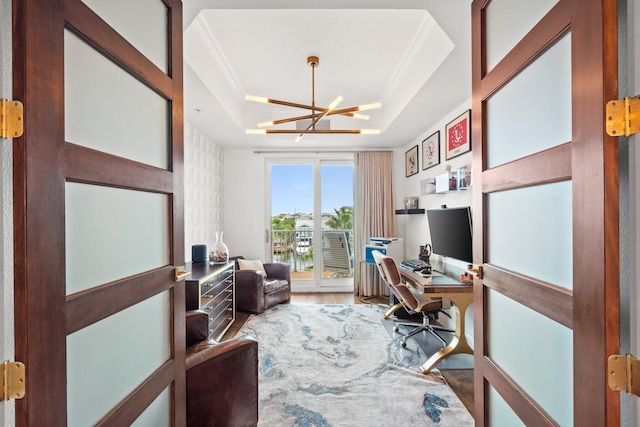 office space with a tray ceiling, a chandelier, crown molding, and wood finished floors