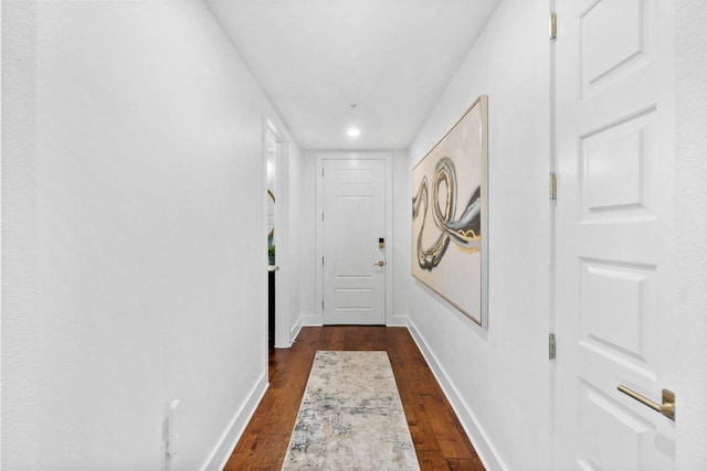hall with baseboards and dark wood-type flooring