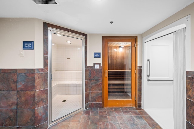 bathroom featuring tile walls, a shower stall, and visible vents