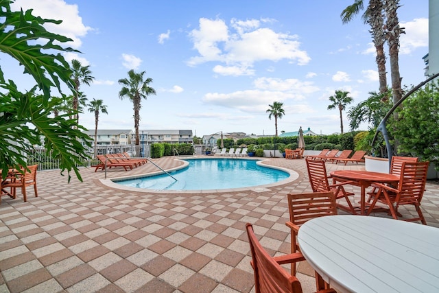 community pool with a patio area and outdoor dining space