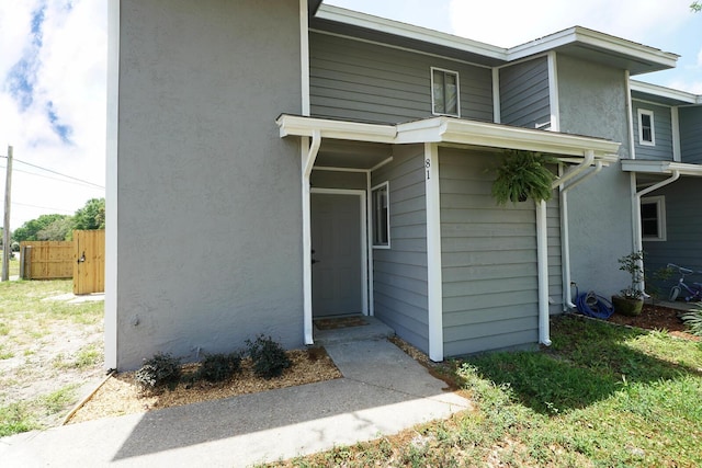 view of front facade featuring stucco siding and fence