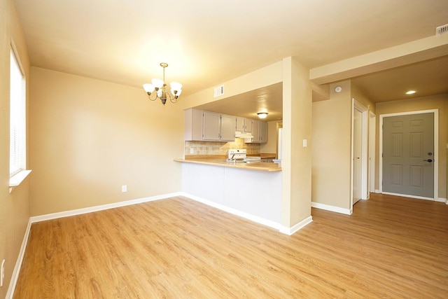 kitchen featuring white appliances, light wood finished floors, a chandelier, and light countertops