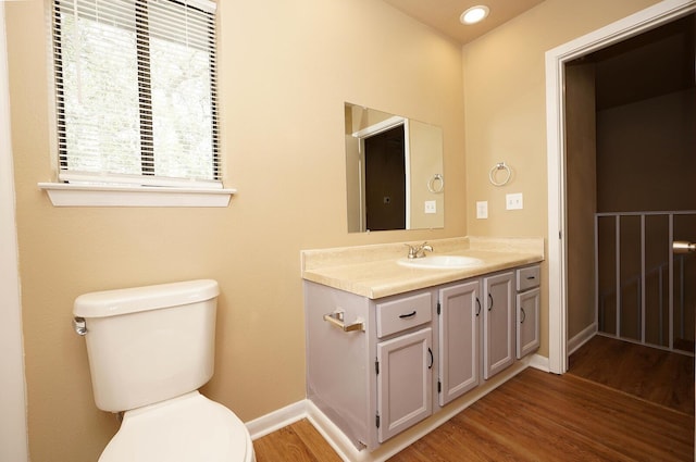 half bathroom with toilet, baseboards, wood finished floors, and vanity
