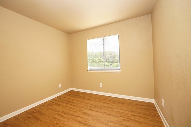 spare room with baseboards and wood finished floors