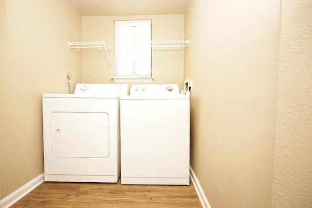 laundry room with laundry area, light wood-style floors, baseboards, and washing machine and clothes dryer