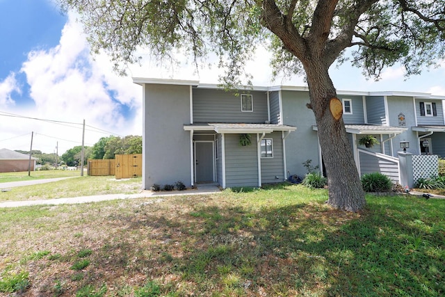 view of front of home with fence, stucco siding, and a front yard