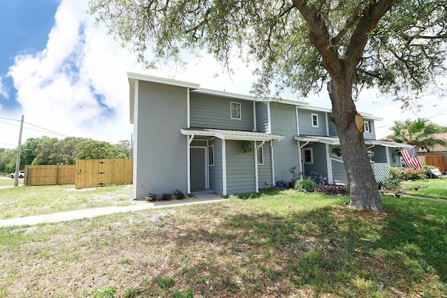 rear view of house featuring stucco siding, a gate, fence, and a lawn
