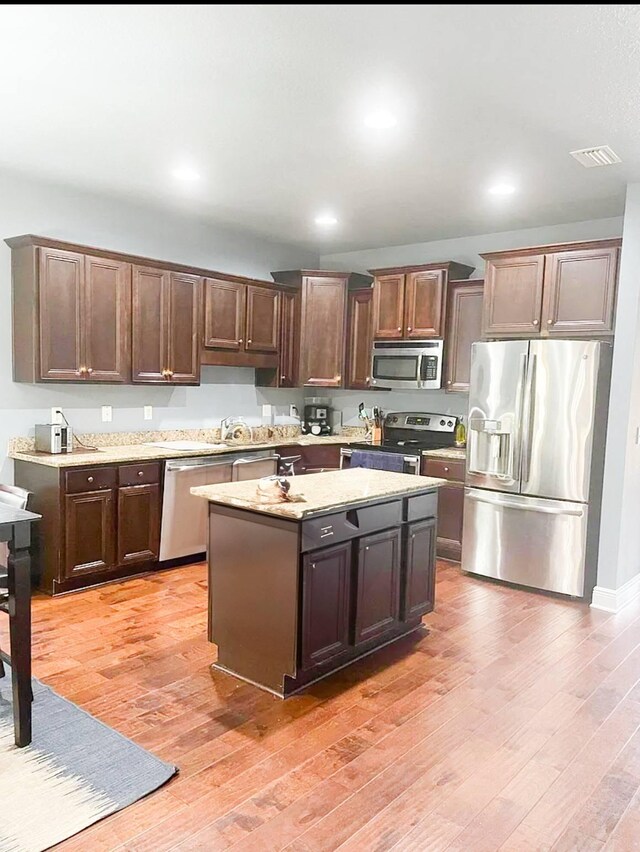 897 Cocobolo Dr, Santa Rosa Beach, FL 32459 - kitchen with stainless steel appliances, light wood-type flooring, a kitchen island, recessed lighting, and dark brown cabinetry