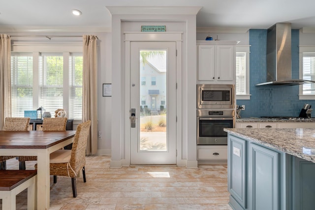 doorway to outside featuring a wealth of natural light, ornamental molding, and light wood-style floors