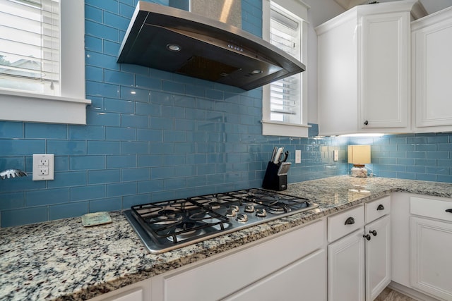 kitchen with white cabinetry, wall chimney range hood, decorative backsplash, and stainless steel gas cooktop