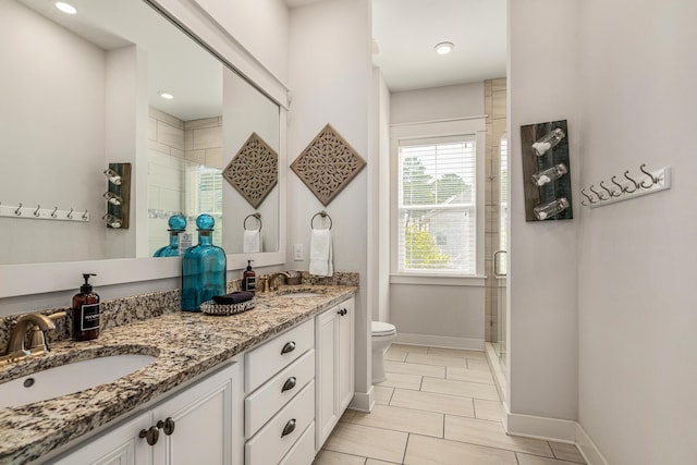 bathroom with double vanity, toilet, a sink, baseboards, and a shower stall