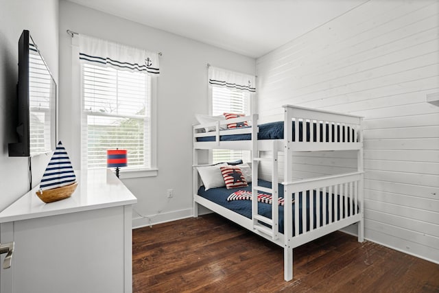 bedroom with wood walls, baseboards, and wood-type flooring