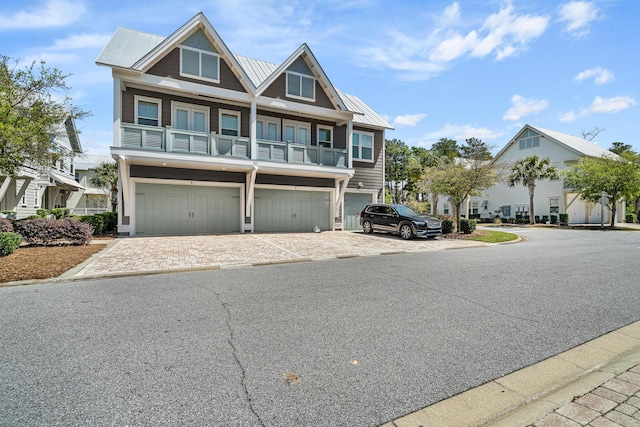 coastal home with metal roof, a standing seam roof, a garage, and driveway