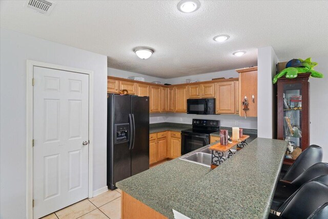 291 Dahlquist Dr, Crestview, FL 32539 - kitchen featuring black appliances, a peninsula, light tile patterned flooring, a kitchen bar, and a textured ceiling