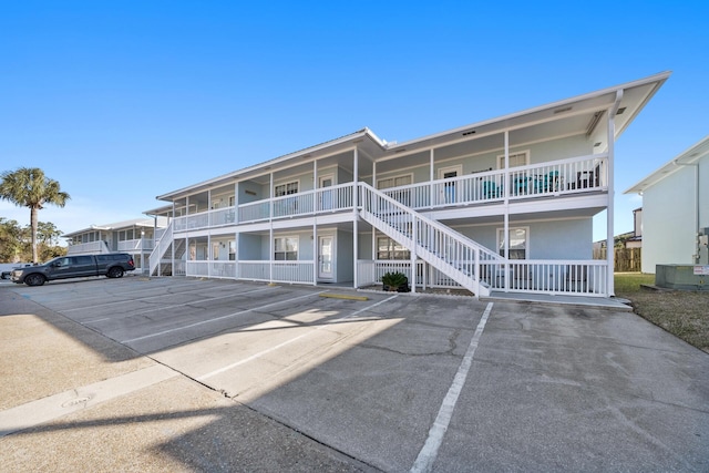 view of property featuring stairway and uncovered parking