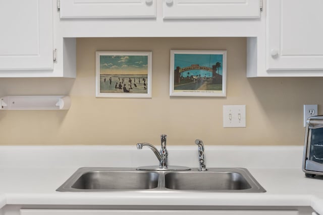 interior details with a sink, light countertops, and white cabinets
