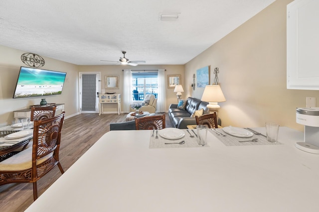 living area featuring baseboards, visible vents, wood finished floors, and a ceiling fan