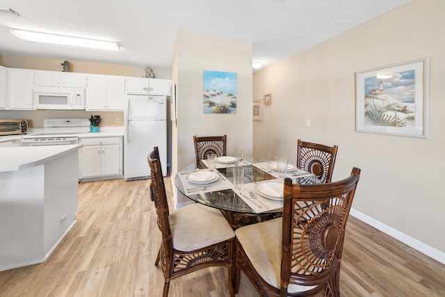 dining area with a textured ceiling, visible vents, a toaster, baseboards, and light wood-style floors