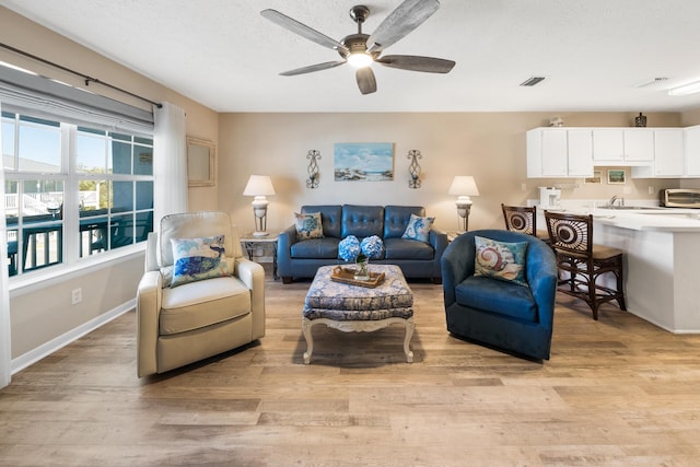 living area with ceiling fan, light wood-style flooring, baseboards, and visible vents