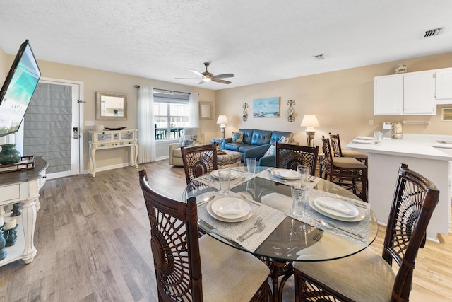 dining room with light wood-type flooring, baseboards, visible vents, and ceiling fan