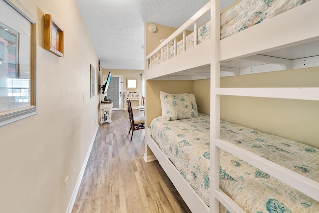 bedroom featuring a textured ceiling, wood finished floors, and baseboards