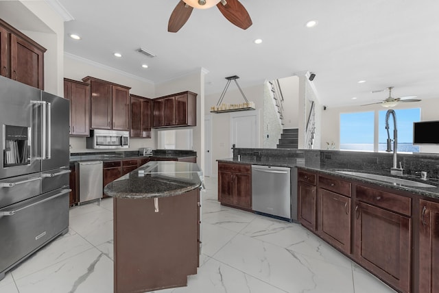 kitchen with ceiling fan, appliances with stainless steel finishes, a sink, light marble finish floors, and ornamental molding