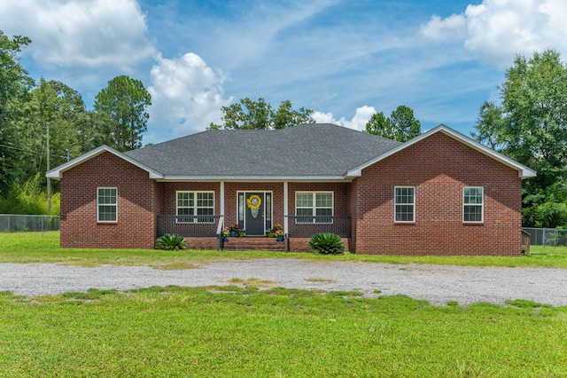 single story home with brick siding, fence, covered porch, roof with shingles, and a front lawn