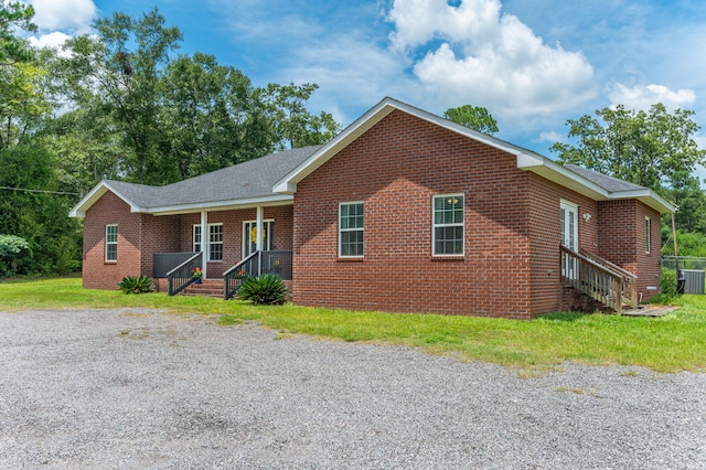 ranch-style home featuring central AC unit, roof with shingles, brick siding, and covered porch
