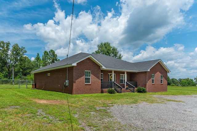 view of front of property with covered porch, brick siding, a front lawn, and fence