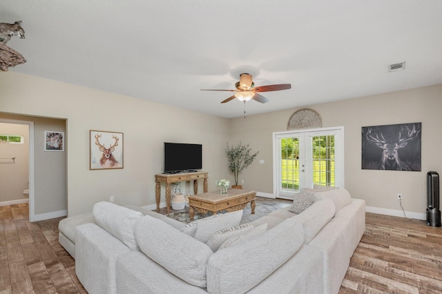 living area featuring a ceiling fan, baseboards, visible vents, and wood finished floors